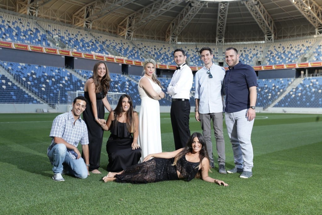 צילומי טרום חתונה, זוג וחברים מלווים, על כר הדשא באצטדיון